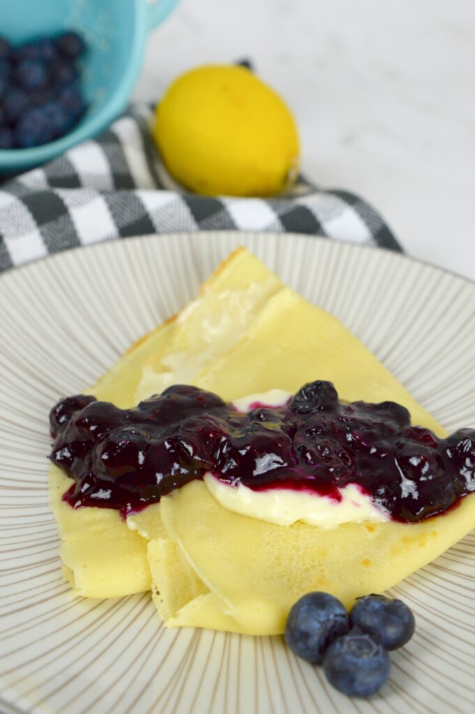 Delicious French-inspired Blueberry Cream Cheese Crepes filled with sweet cream cheese and topped with bursting blueberries.