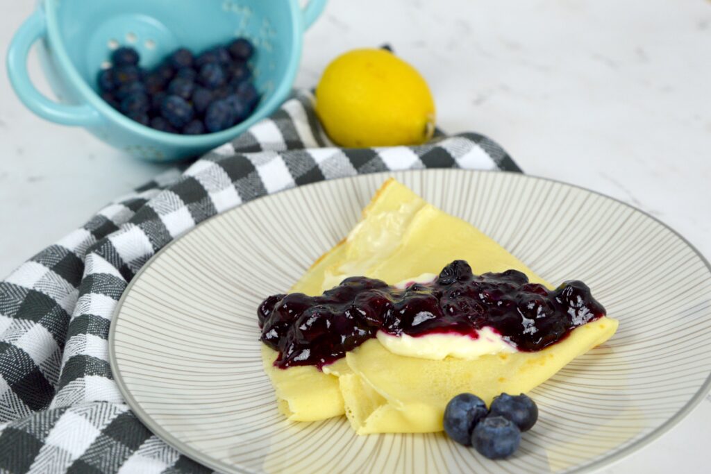 Delicious French-inspired Blueberry Cream Cheese Crepes filled with sweet cream cheese and topped with bursting blueberries.