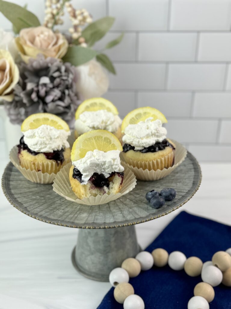 These Lemon Blueberry Poke Cupcakes are easy to make using a boxed cake mix combined with a homemade lemon blueberry sauce and homemade whipped topping.