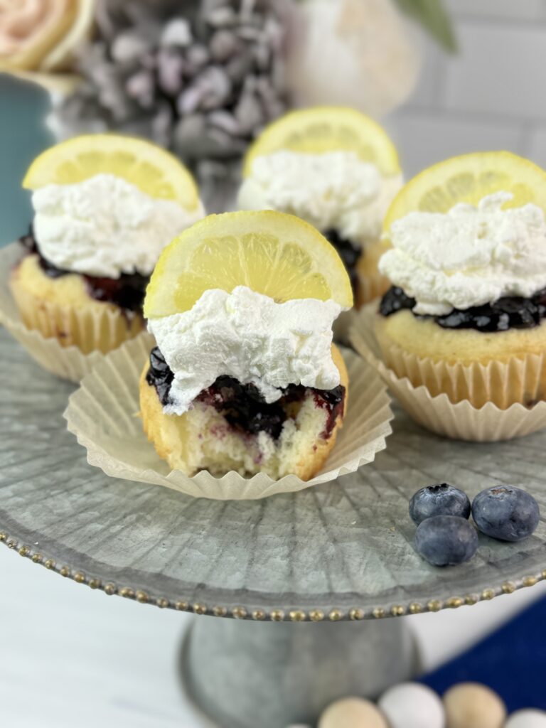 These Lemon Blueberry Poke Cupcakes are easy to make using a boxed cake mix combined with a homemade lemon blueberry sauce and homemade whipped topping.