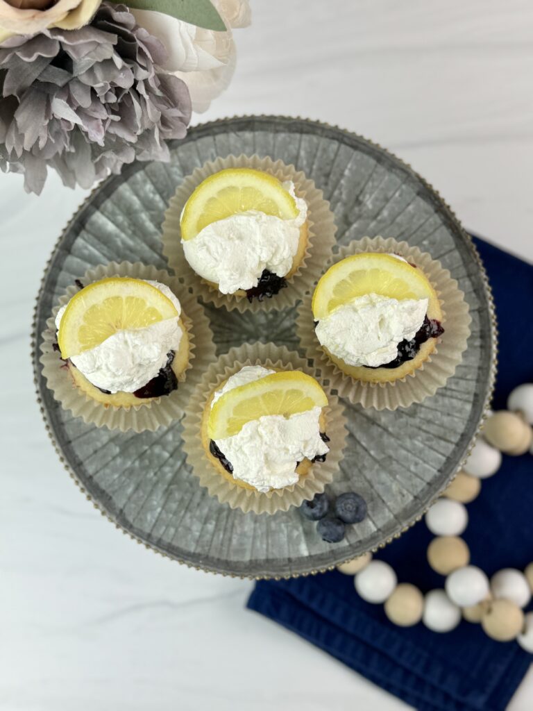 These Lemon Blueberry Poke Cupcakes are easy to make using a boxed cake mix combined with a homemade lemon blueberry sauce and homemade whipped topping.