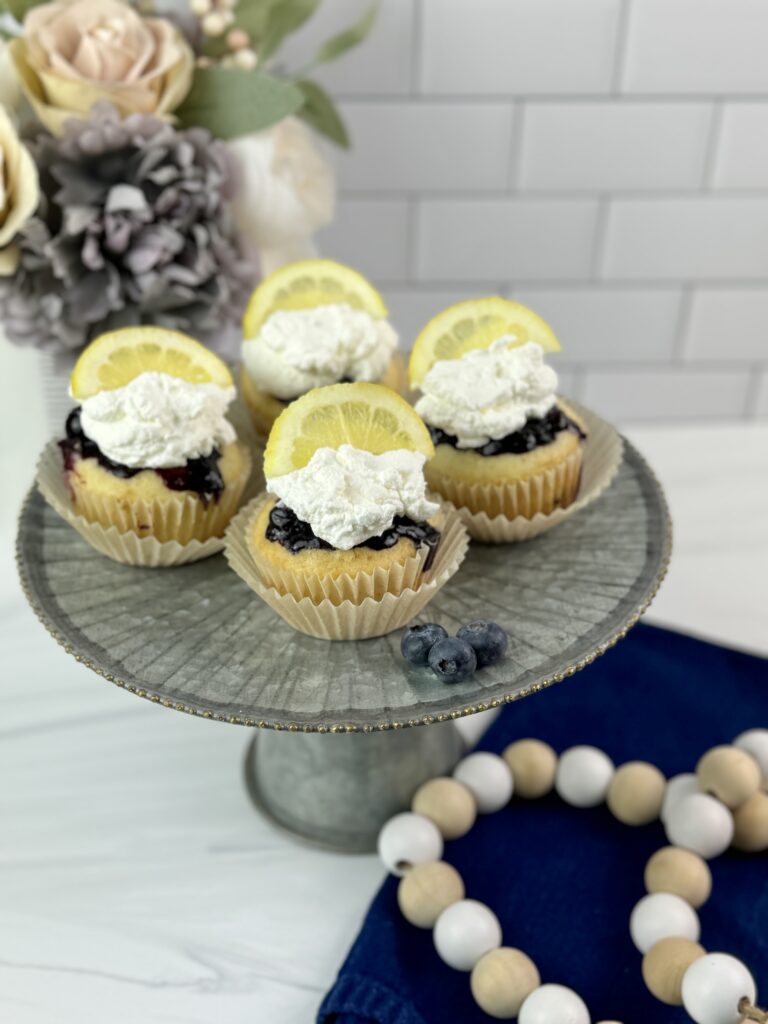 These Lemon Blueberry Poke Cupcakes are easy to make using a boxed cake mix combined with a homemade lemon blueberry sauce and homemade whipped topping.